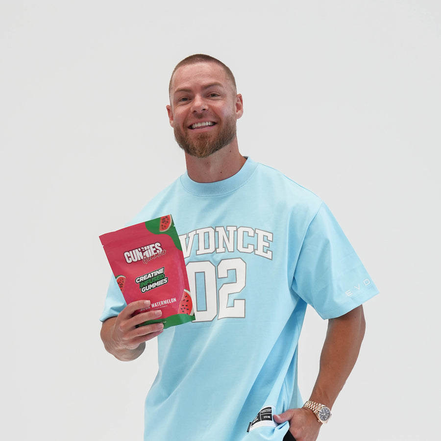 Man in a blue tee holding a bag of Sour Watermelon Cunnies creatine gummies